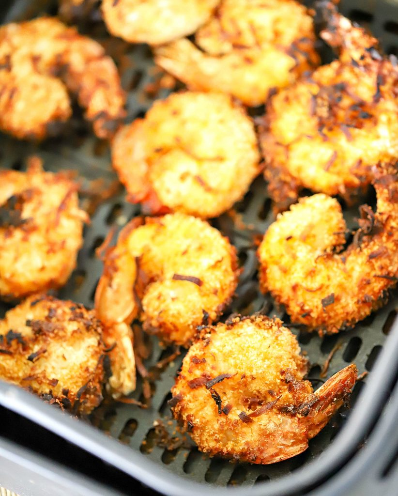 Air fryer basket with 10 cooked coconut shrimp inside