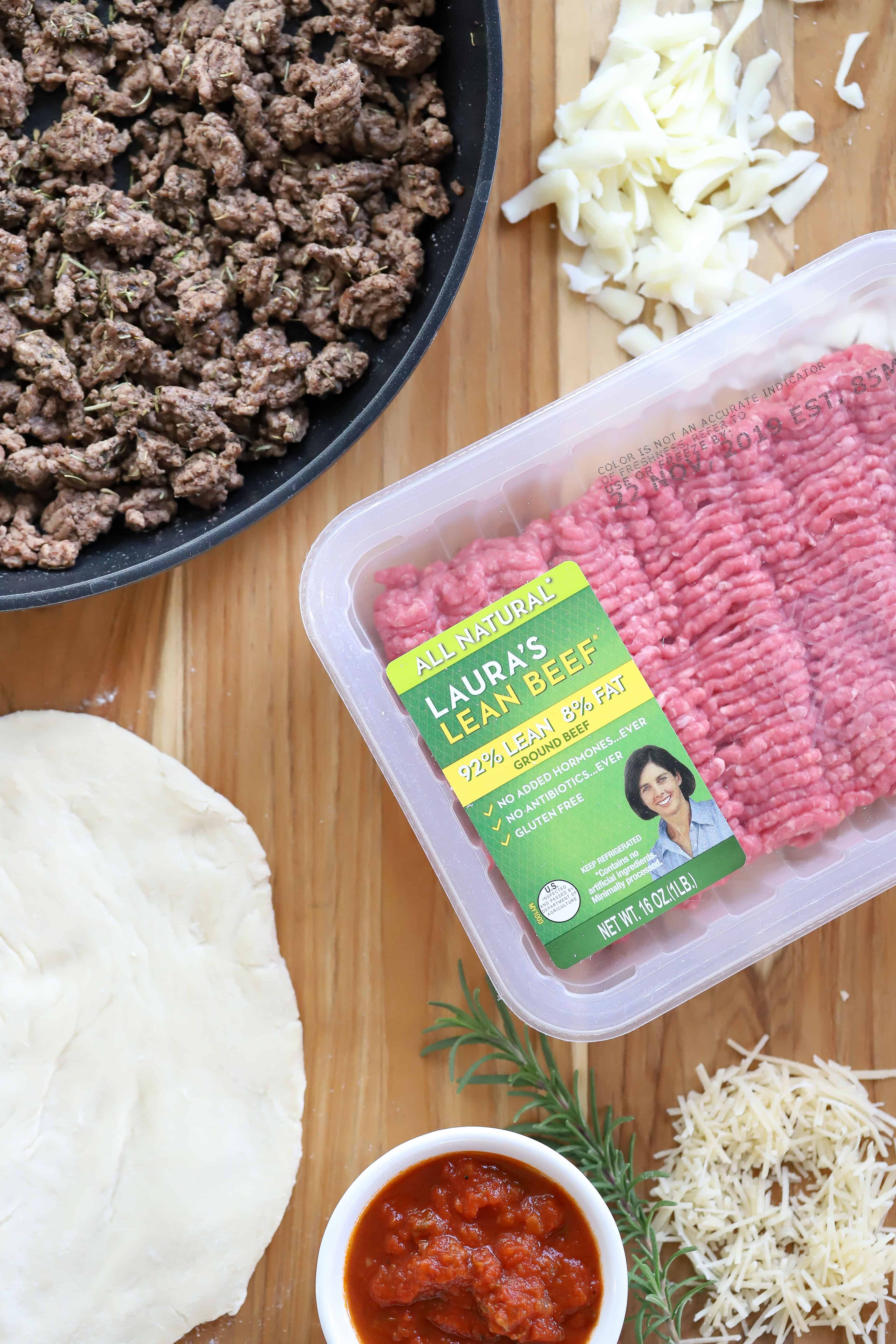 Overhead shot of Laura's Ground Beef, pizza dough, pizza sauce, cheese and ground beef mixture. #ad