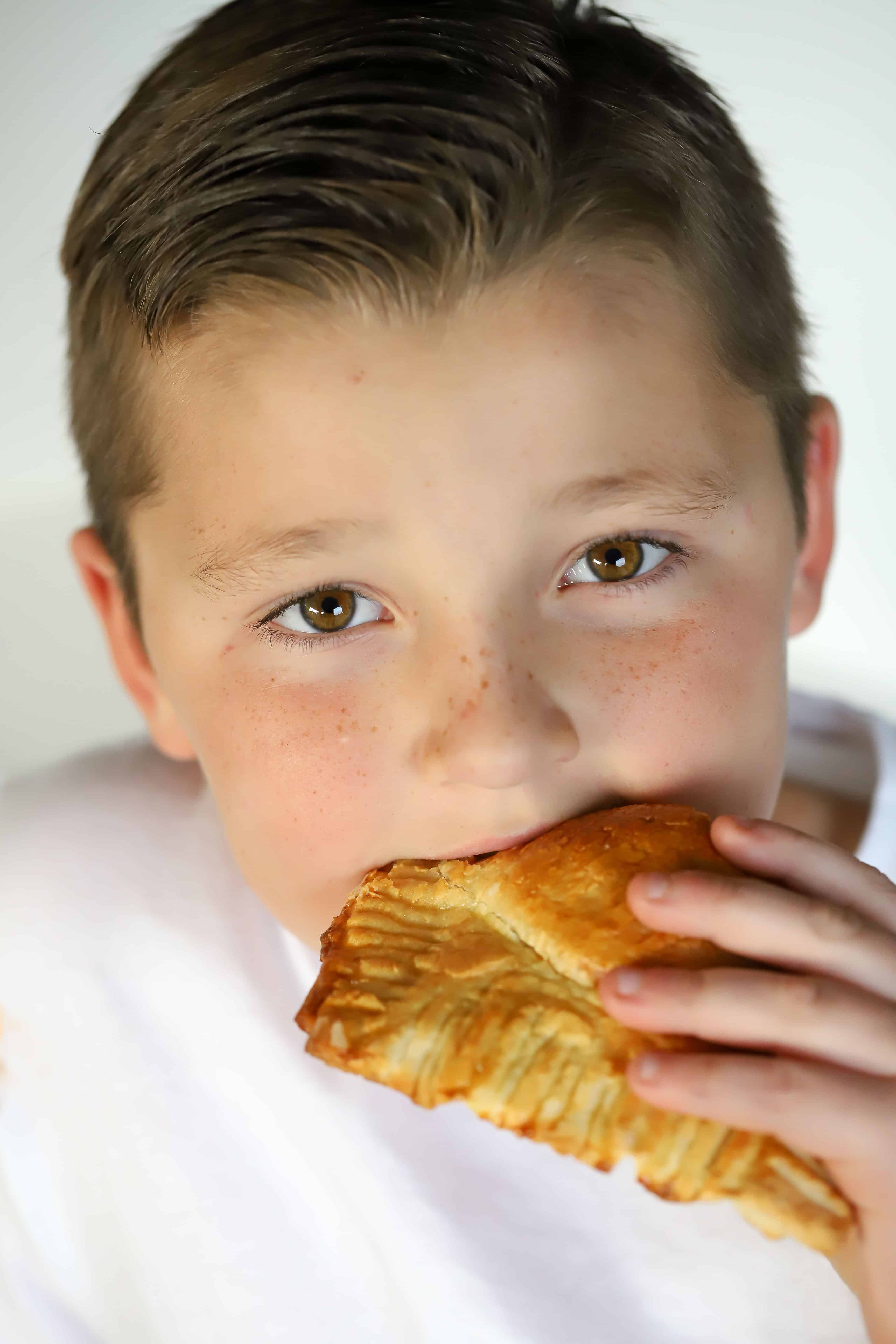 Cute little boy taking a bite of a cooked pizza pocket! #ad