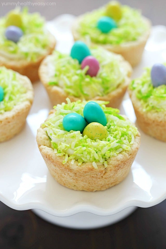 Need a fun treat to make for an Easter get together? Make these darling Easter Nest Sugar Cookie Cups! Sugar cookie dough cooked in a muffin tin, filled with vanilla frosting, topped with green tinted coconut and M&M eggs to look like a little bird's nest. So cute and great for spring! #truvia