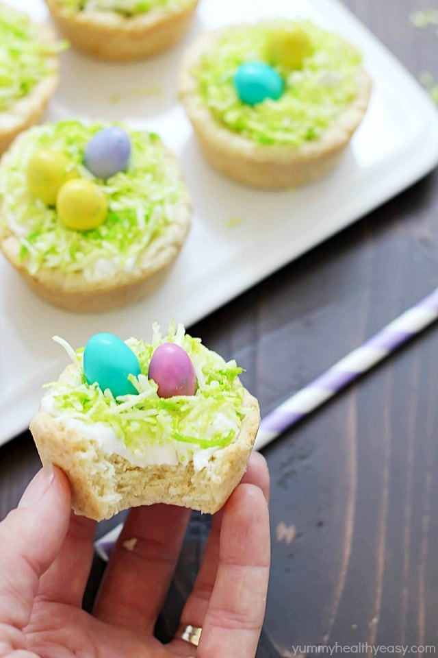 Need a fun treat to make for an Easter get together? Make these darling Easter Nest Sugar Cookie Cups! Sugar cookie dough cooked in a muffin tin, filled with vanilla frosting, topped with green tinted coconut and M&M eggs to look like a little bird's nest. So cute and great for spring! #truvia